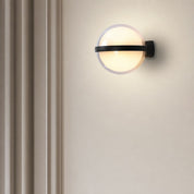 Glowing round wall sconce with a black horizontal band on a pale wall.