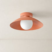 Coral ceiling light with wide saucer shade and white globe bulb on a pale ceiling.
