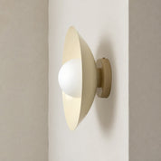Cream wall sconce with a white globe bulb mounted on a neutral wall.