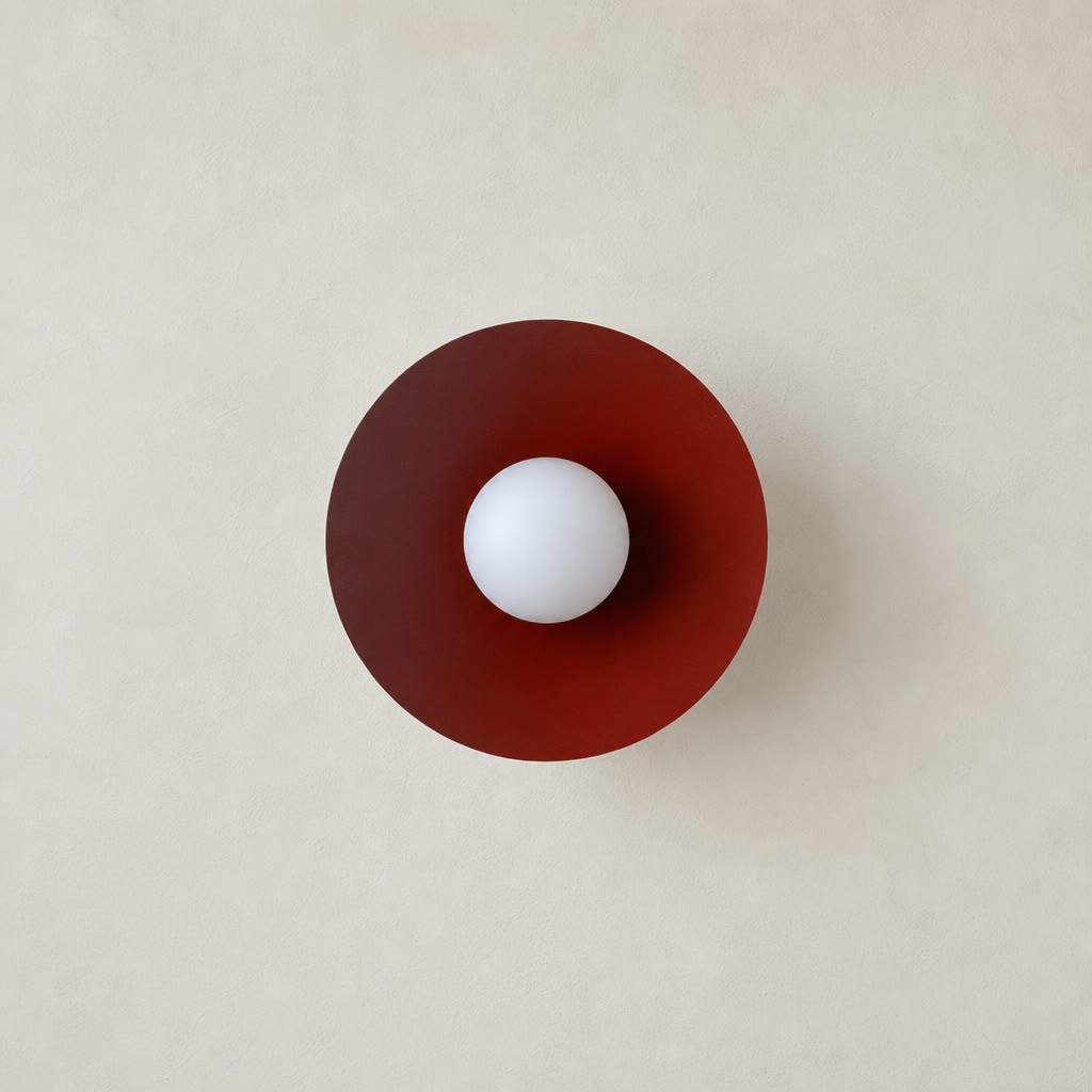 Burgundy circular lamp shade with a central white globe on a warm neutral wall.