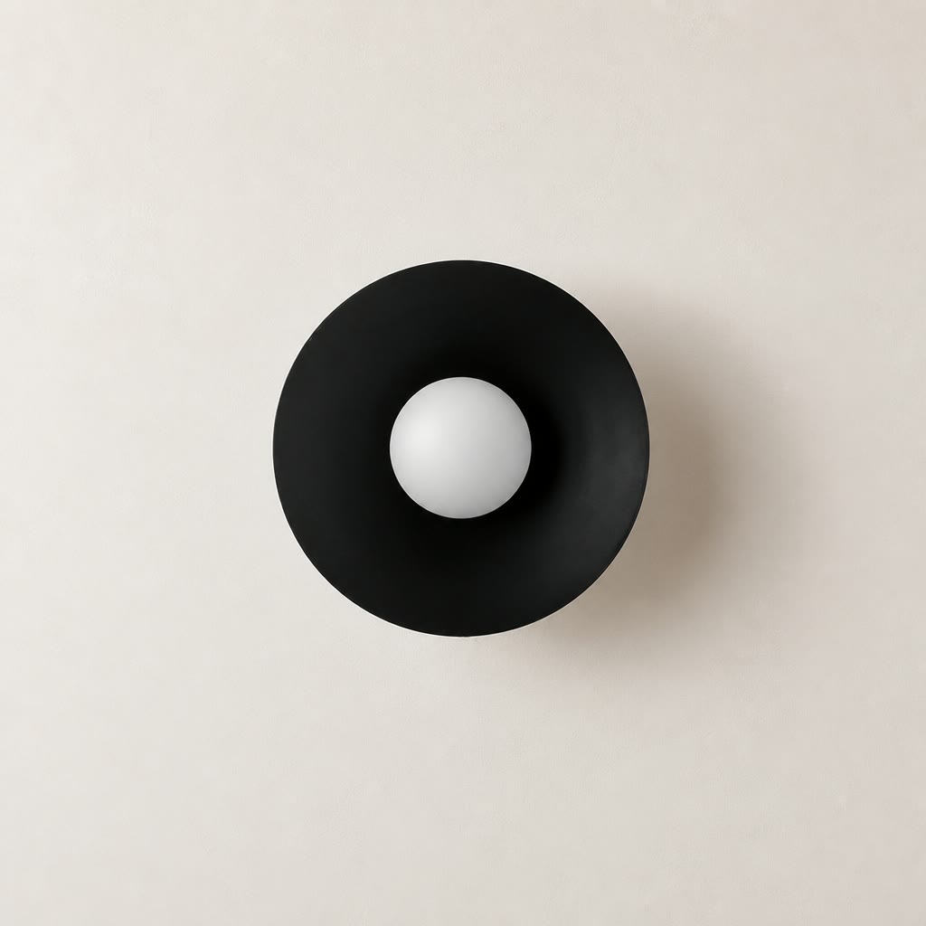 Black circular wall sconce with a white spherical bulb centered on a pale wall.