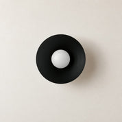 Black circular wall sconce with a white spherical bulb centered on a pale wall.