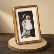 Wood and brass photo frame with a girl and dog portrait leaning on a wooden slice.