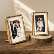 Two wooden and brass photo frames displayed on a rustic tabletop.