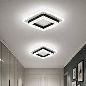 Two glowing square ceiling lights with white frames and black trim in a modern hallway.
