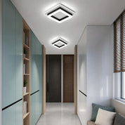 Two glowing square black-and-white LED ceiling lights in a modern hallway