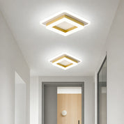 Two glowing square white and gold ceiling lights in a modern hallway.