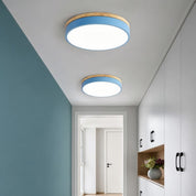 Two round blue and wood flush ceiling lights illuminating a modern hallway with cabinets.