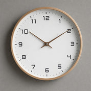 Round wooden wall clock with a white face and brown hands on a gray wall.