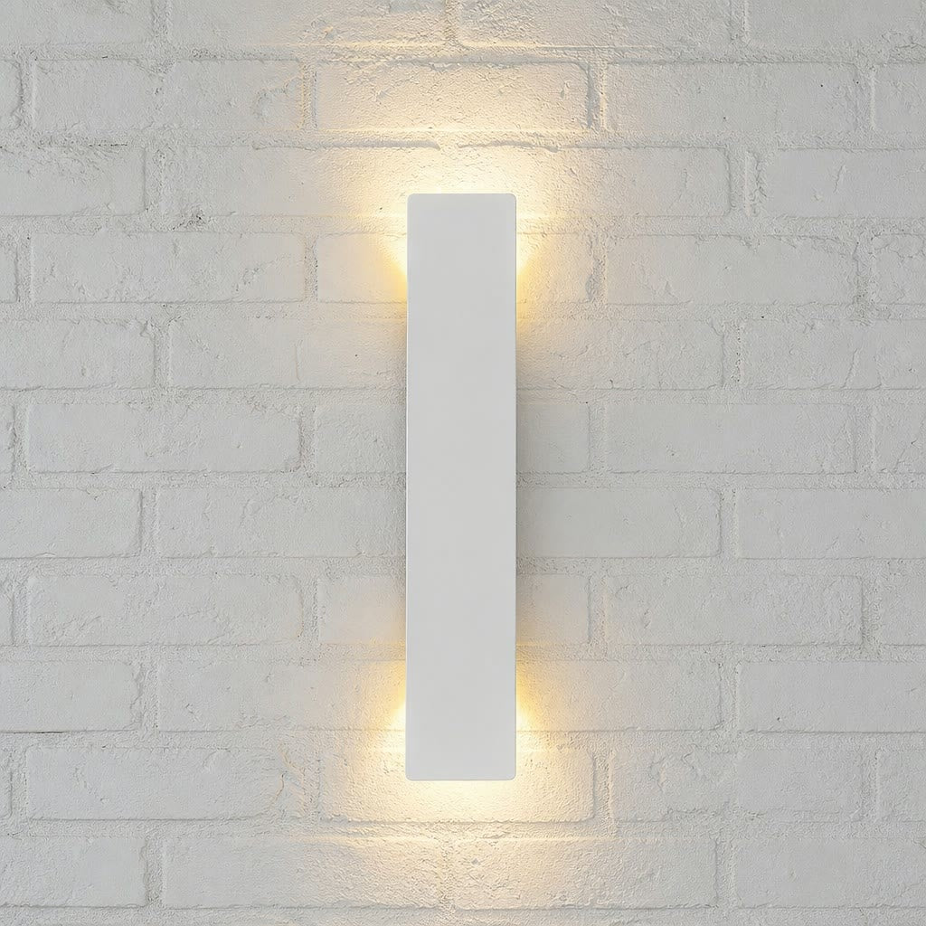 Slim white rectangular wall sconce glowing warmly on a pale textured brick wall.