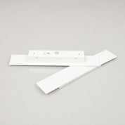 White ceiling fan blade assembly with rectangular motor housing on a light gray surface.