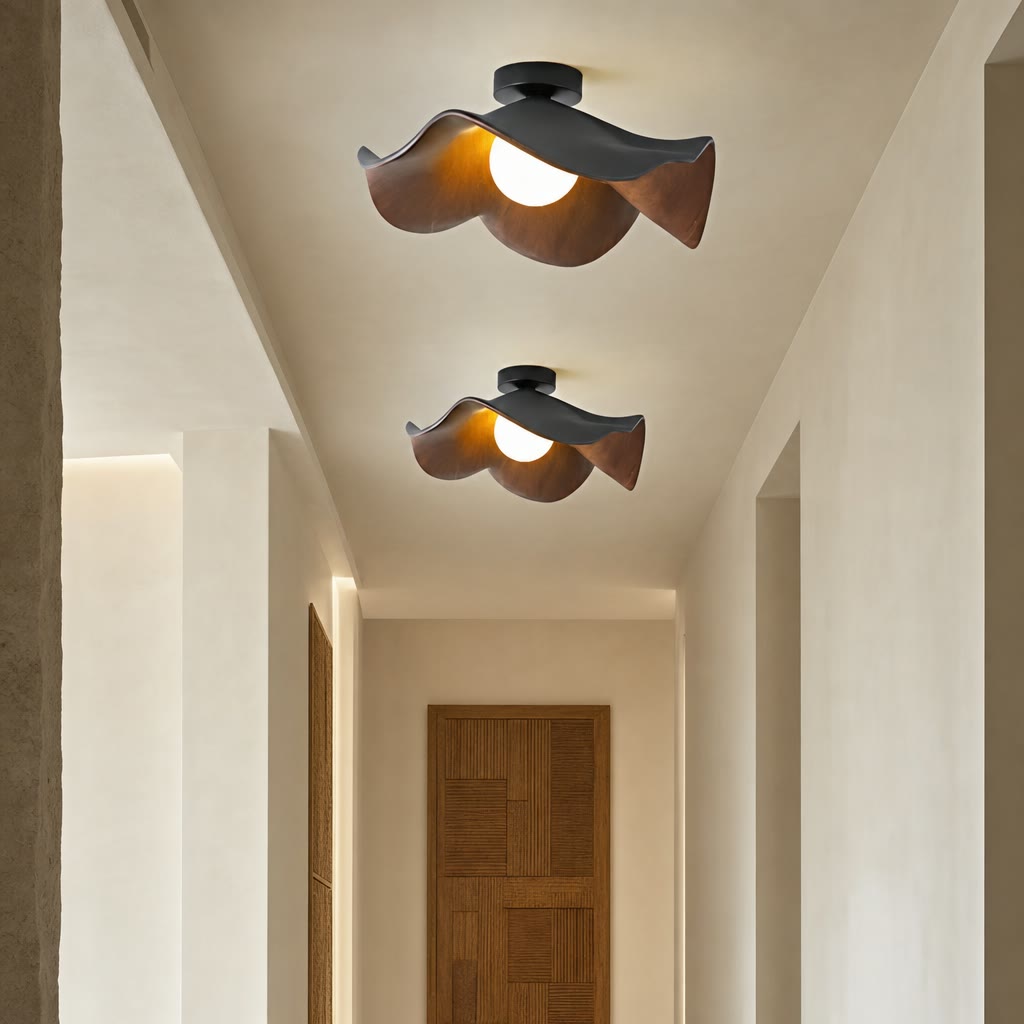 Two sculptural wood and black ceiling lights with glowing bulbs in a warm hallway.