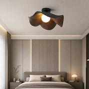 Wood-toned petal ceiling fan light with a glowing globe above a modern bedroom.