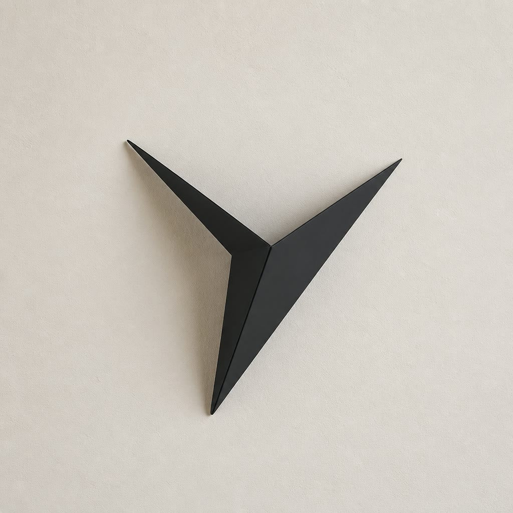 Black angular three-point wall decor mounted on a pale neutral wall.