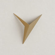 Gold angular origami bird wall decor centered on a pale textured wall.