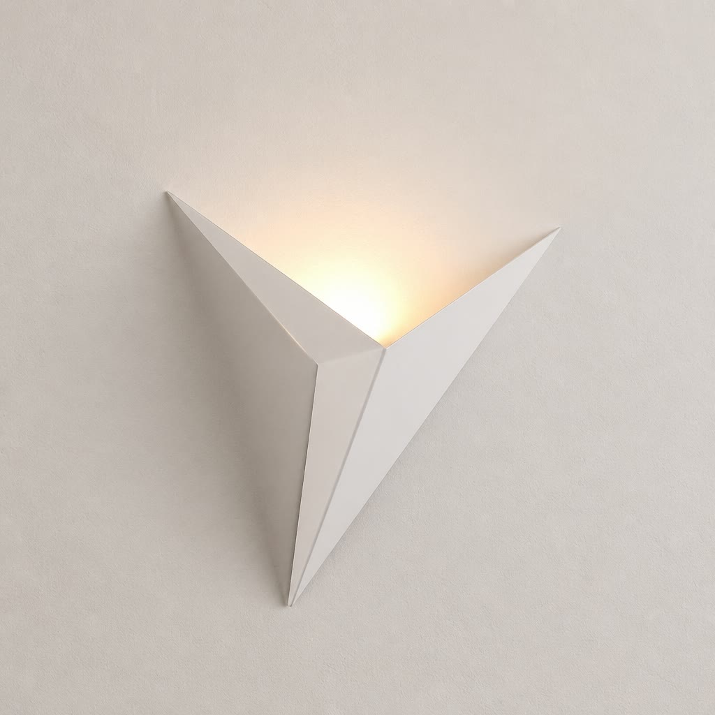 White angular wall sconce glowing warmly on a pale minimalist wall.
