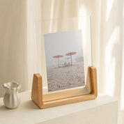 Wooden acrylic photo frame displaying a beach umbrella print on a softly lit shelf.