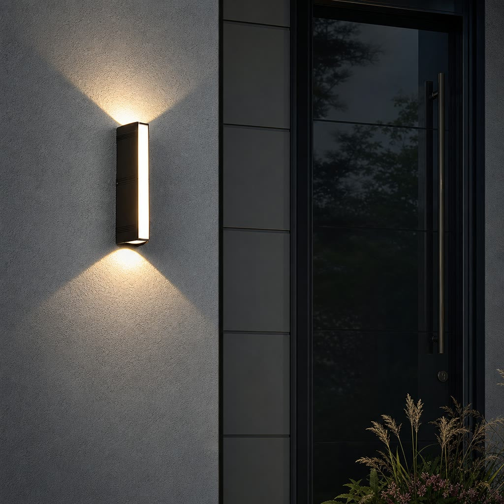 Rectangular black outdoor wall light glowing on a textured wall beside a dark front door.