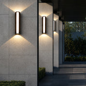 Three lit vertical wall sconces mounted on textured exterior columns.