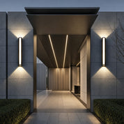 Modern outdoor wall sconces illuminate a sleek entrance with warm up and down light.