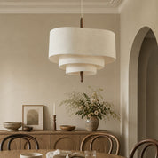 Tiered cream fabric pendant light hanging above a warm neutral dining room.