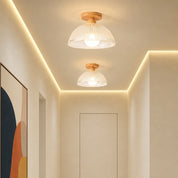 Two warm ceiling lights with white ribbed shades and wood mounts in a modern hallway.