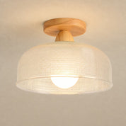 Warm glowing ceiling light with a wood mount and cream woven drum shade.
