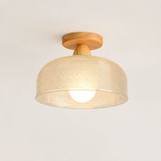 Woven beige ceiling light with wooden mount and glowing bulb on a plain light background.