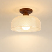 Warm ceiling light with a woven beige shade and wooden mount against a plain ceiling.