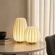 Two warm glowing ribbed table lamps with gold bases on a marble side table.