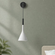 White cone wall pendant lamp with black mount and cord against a muted green wall.