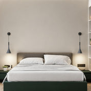 Gray pendant lamps flank a white bed with pillows and a low dark green platform.
