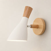 White and wood wall sconce with a glowing conical shade on a round wooden mount.