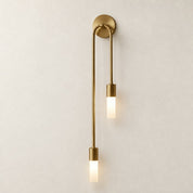 Brass double pendant wall sconce with two glowing frosted rectangular shades.