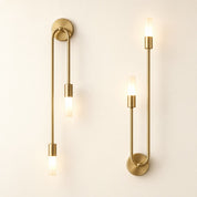 Two matching brass wall sconces with slim rods and glowing frosted cylindrical bulbs.