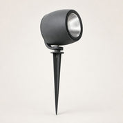 Black cylindrical garden spotlight with silver reflector and ground spike on a light background.