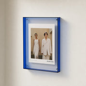 Blue acrylic wall-mounted display frame holding a white fashion poster.
