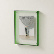 Green translucent wall-mounted display frame holding The Kinfolk Home book