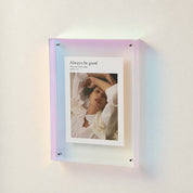 Iridescent acrylic wall frame holding a white photo print with portrait and title text.