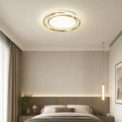 Gold circular ceiling light glowing above a modern bedroom with a matching pendant lamp.