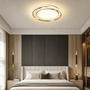 Gold circular LED ceiling light glowing above a modern bedroom