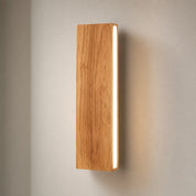 Vertical wooden wall light with a bright white side strip on a soft gray wall.