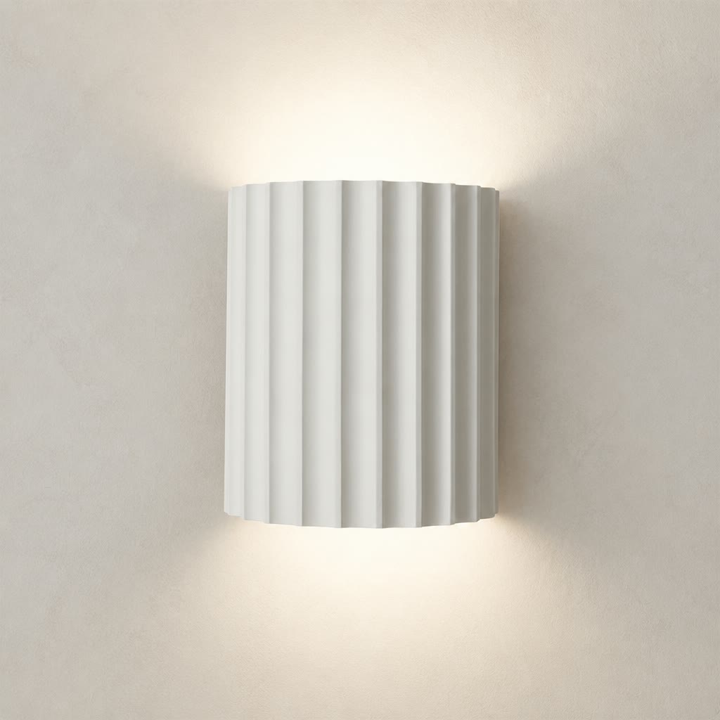 White ribbed cylindrical wall sconce glowing warmly on a plain wall
