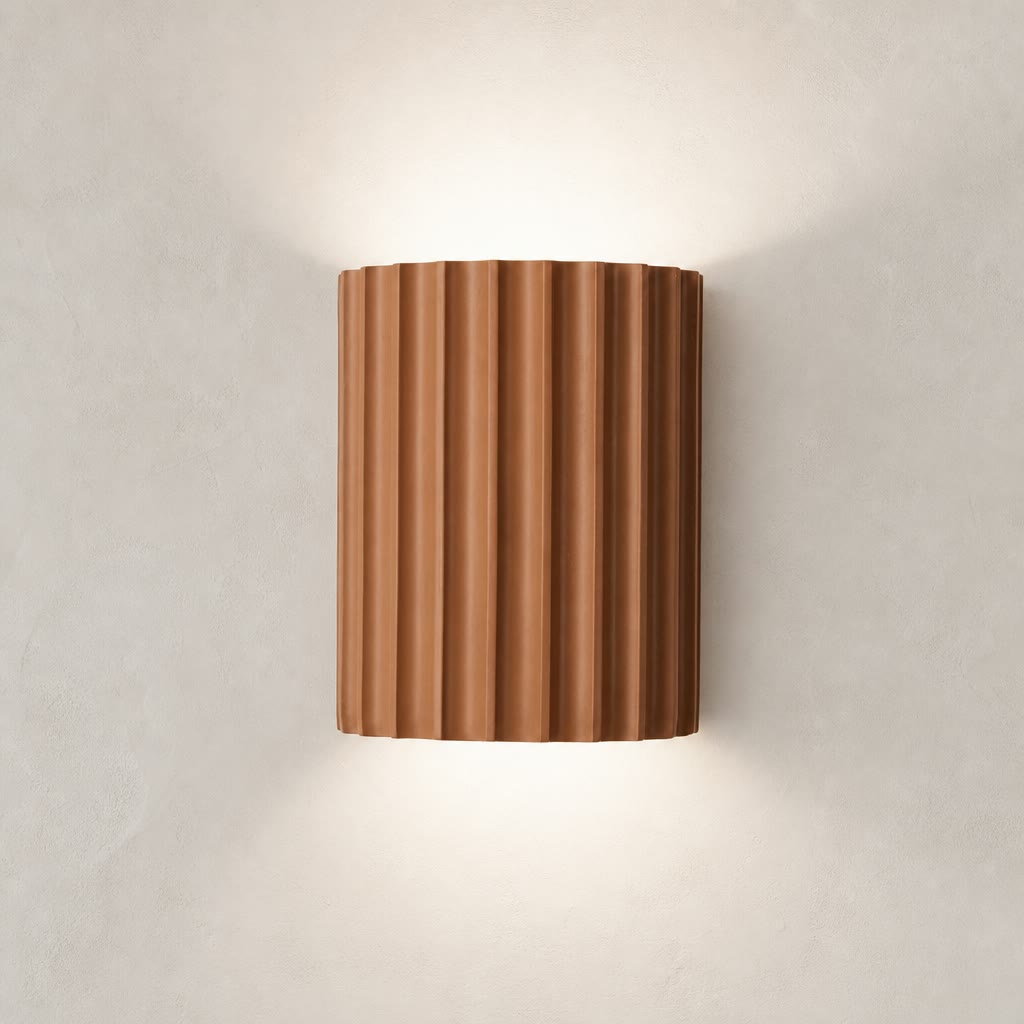 Ribbed terracotta cylindrical wall sconce casting soft light on a neutral wall.