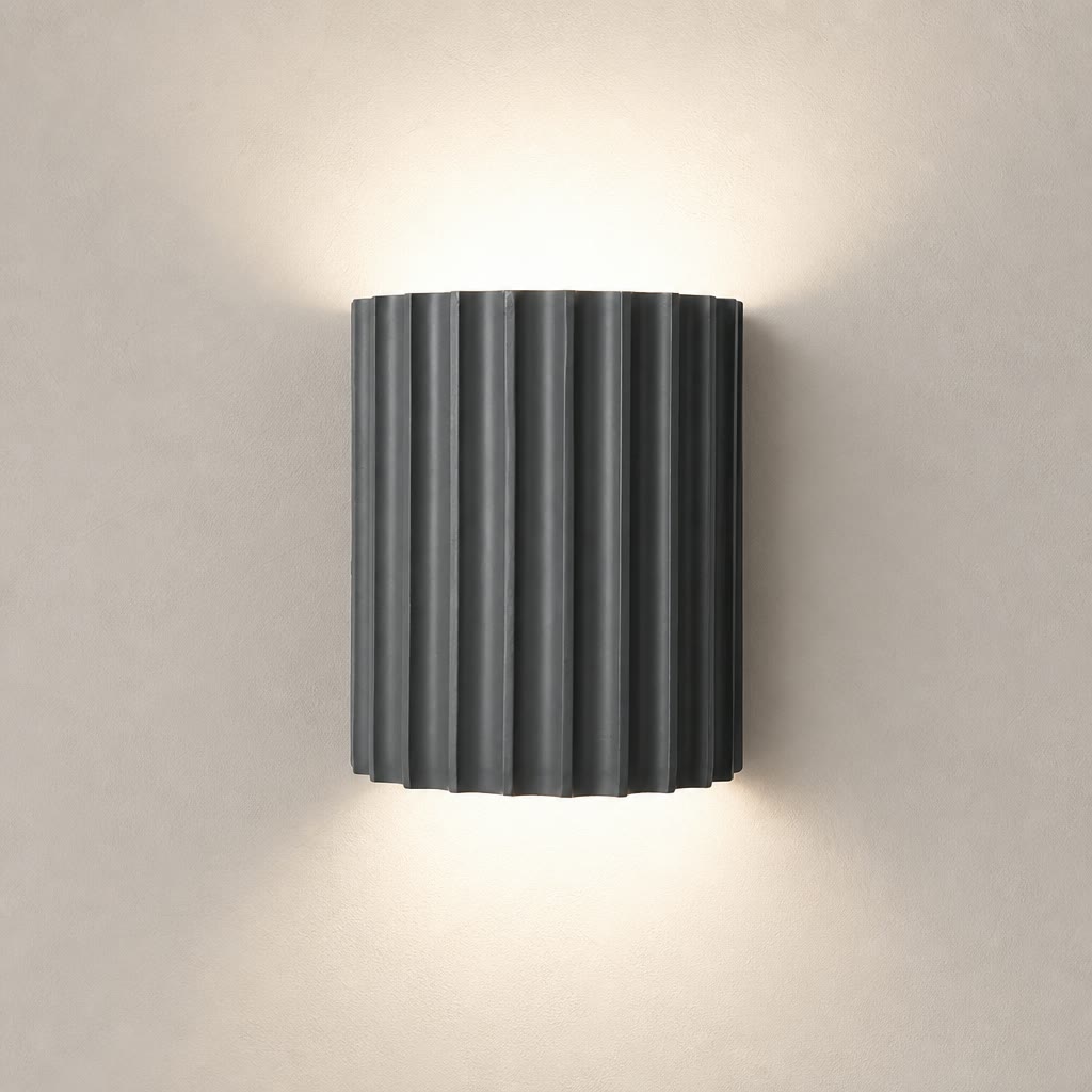 Dark ribbed cylindrical wall sconce emitting warm light above and below.