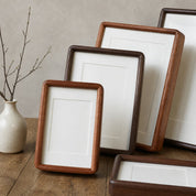 Rounded wooden picture frames with white mats arranged on a wooden tabletop.