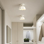Two white wavy-edged ceiling lights in a minimalist wardrobe hallway.