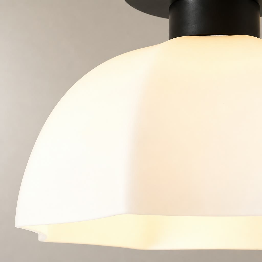 Close-up of a glowing cream dome pendant lamp with a black fixture.