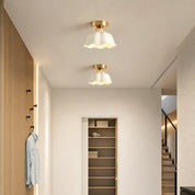 Two white scalloped ceiling lights with gold mounts illuminate a modern hallway.