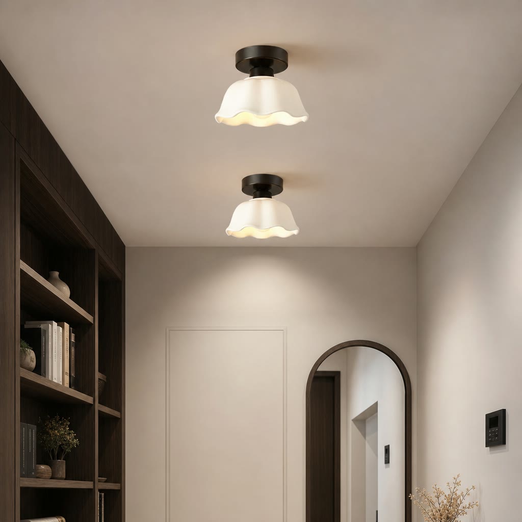 Two cream wavy glass flush mount ceiling lights in a modern hallway with a bookshelf and arched mirror.